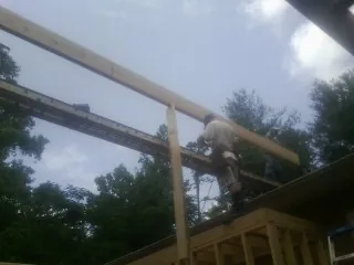 Carpenter setting a ridge beam over a new addition frame — Ice Dam Removal by Roofing Brothers in Logansport
