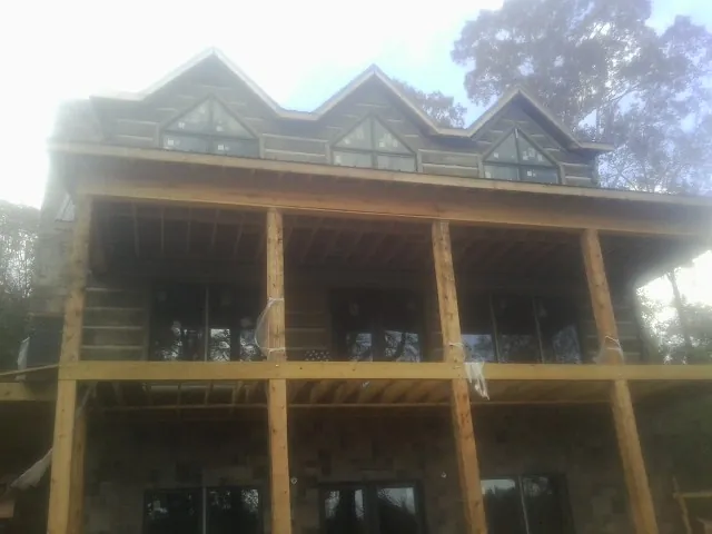 Dormers and porch framing on a large log home under construction — Roof Coating work by our crew in Logansport