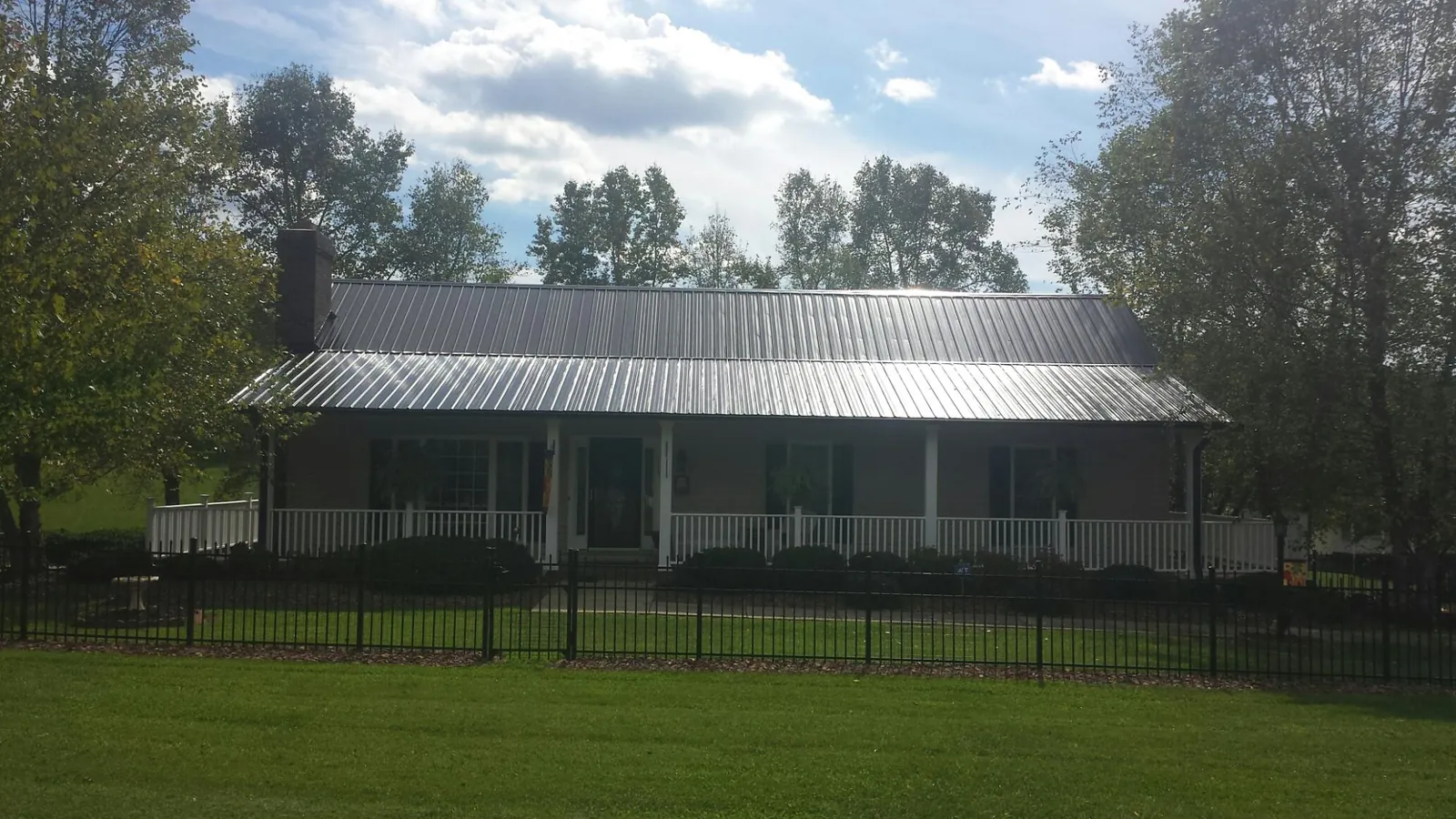 Gray metal roof on a brick ranch with a full width front porch — Gutter Guard Installation work by our crew in Logansport