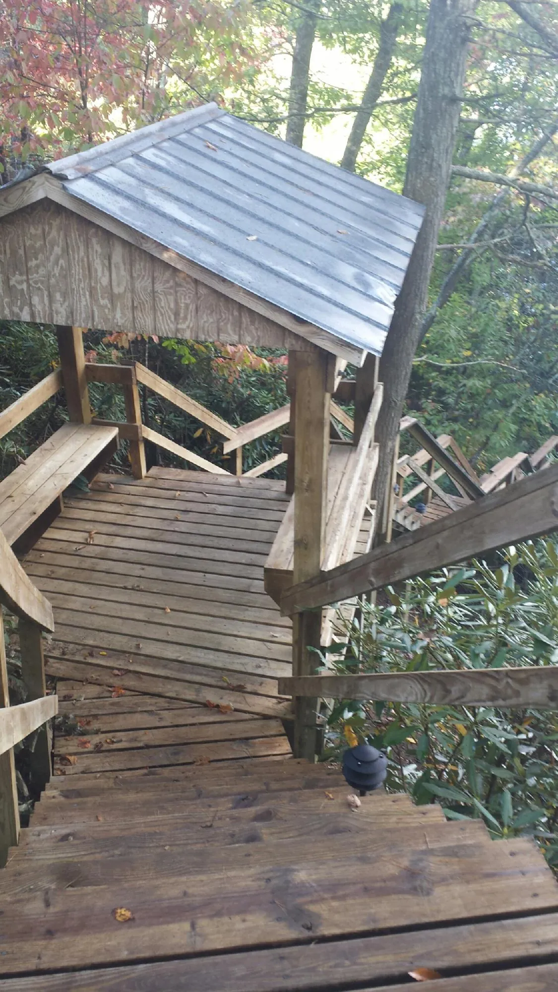 Metal roofed shelter over wooden steps on a wooded walkway — Skylight Repair & Installation work by our crew in Logansport