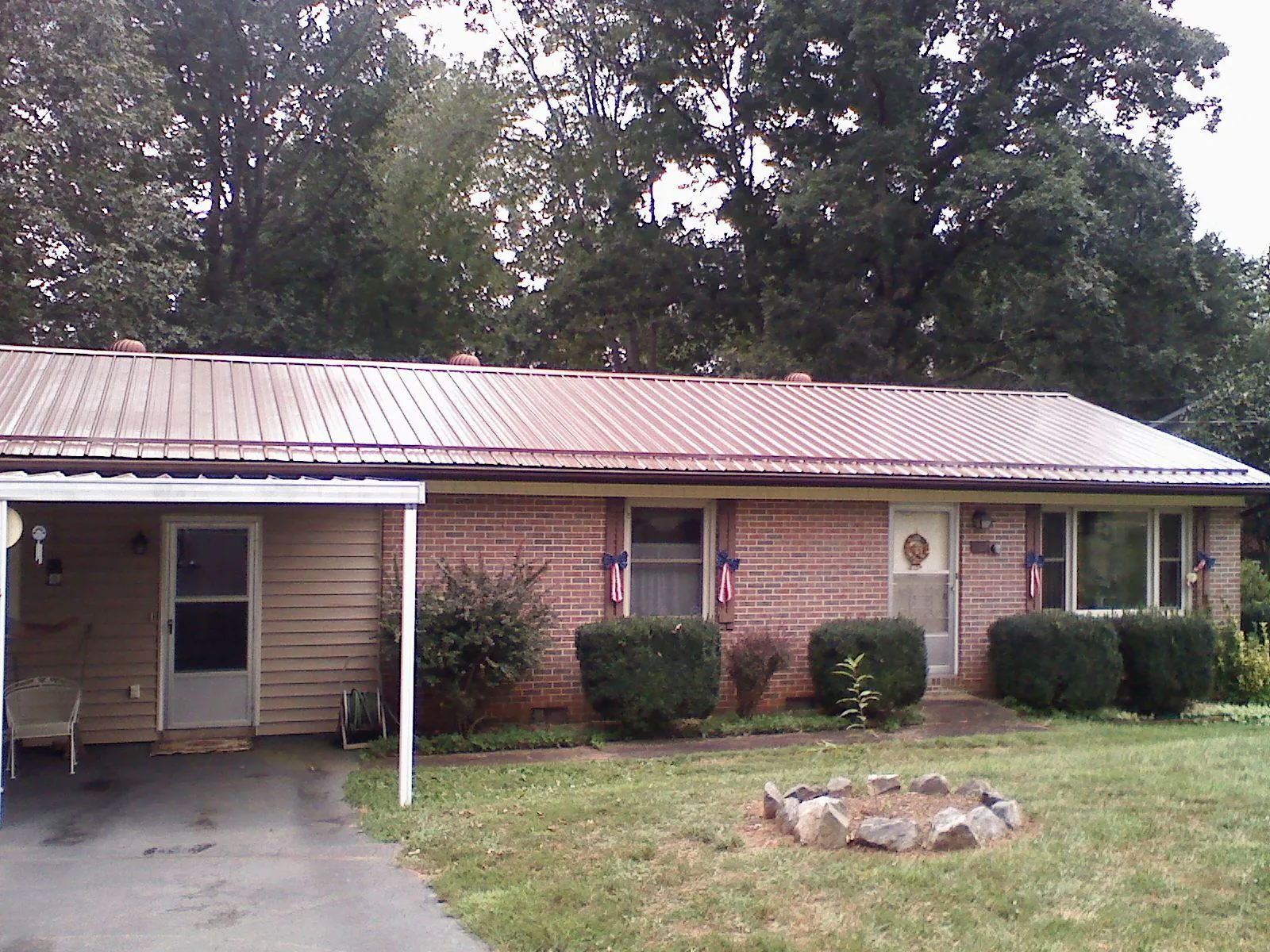 Bronze metal roof and carport on a brick ranch home — Roof Repair work by our crew in Logansport