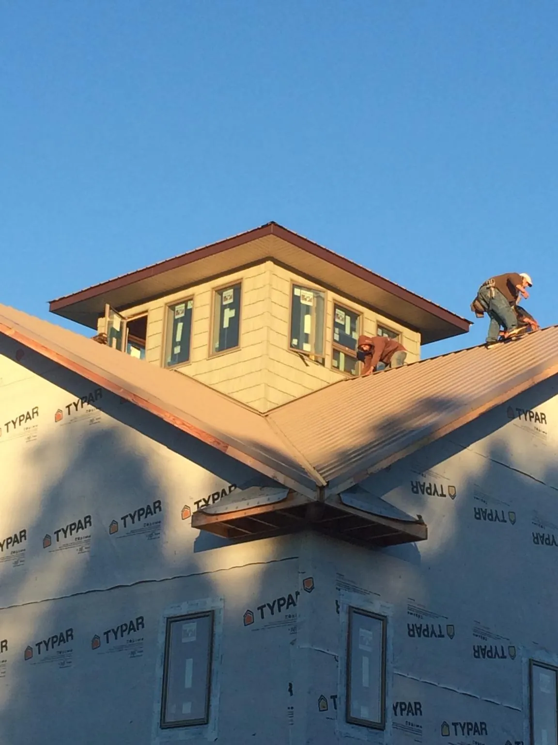 Roofers working around a rooftop cupola on a new metal roof at sunset — Roof Waterproofing in Logansport by Roofing Brothers